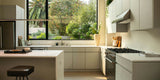 Modern minimalist kitchen with light cabinets, a white island, gas stove, and large window overlooking greenery